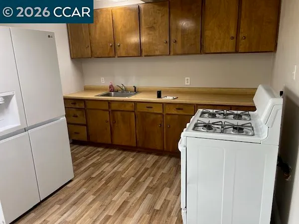 a kitchen with stainless steel appliances granite countertop a refrigerator a stove and a sink with wooden cabinets