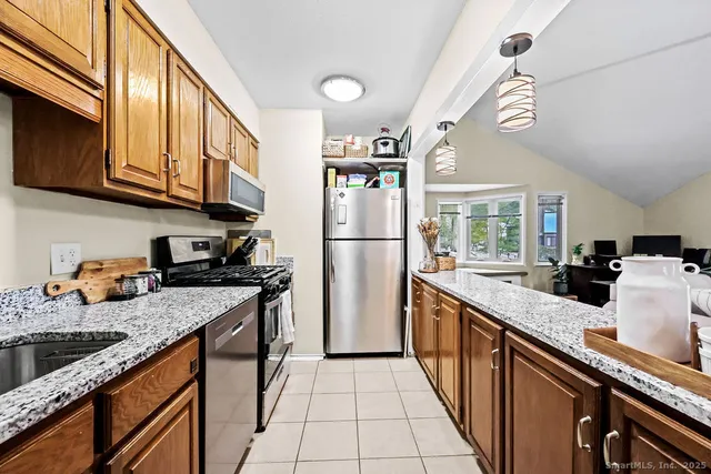 a kitchen with stainless steel appliances granite countertop a sink a stove and a refrigerator