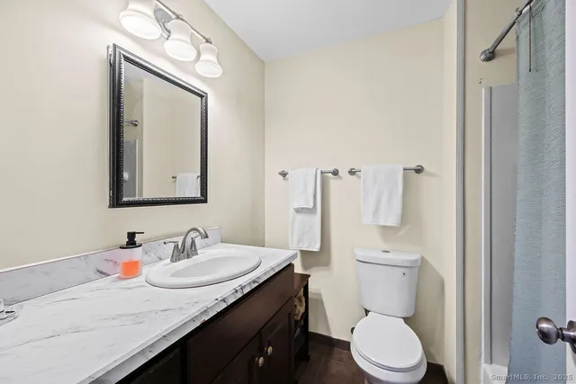a bathroom with a granite countertop sink mirror vanity and toilet