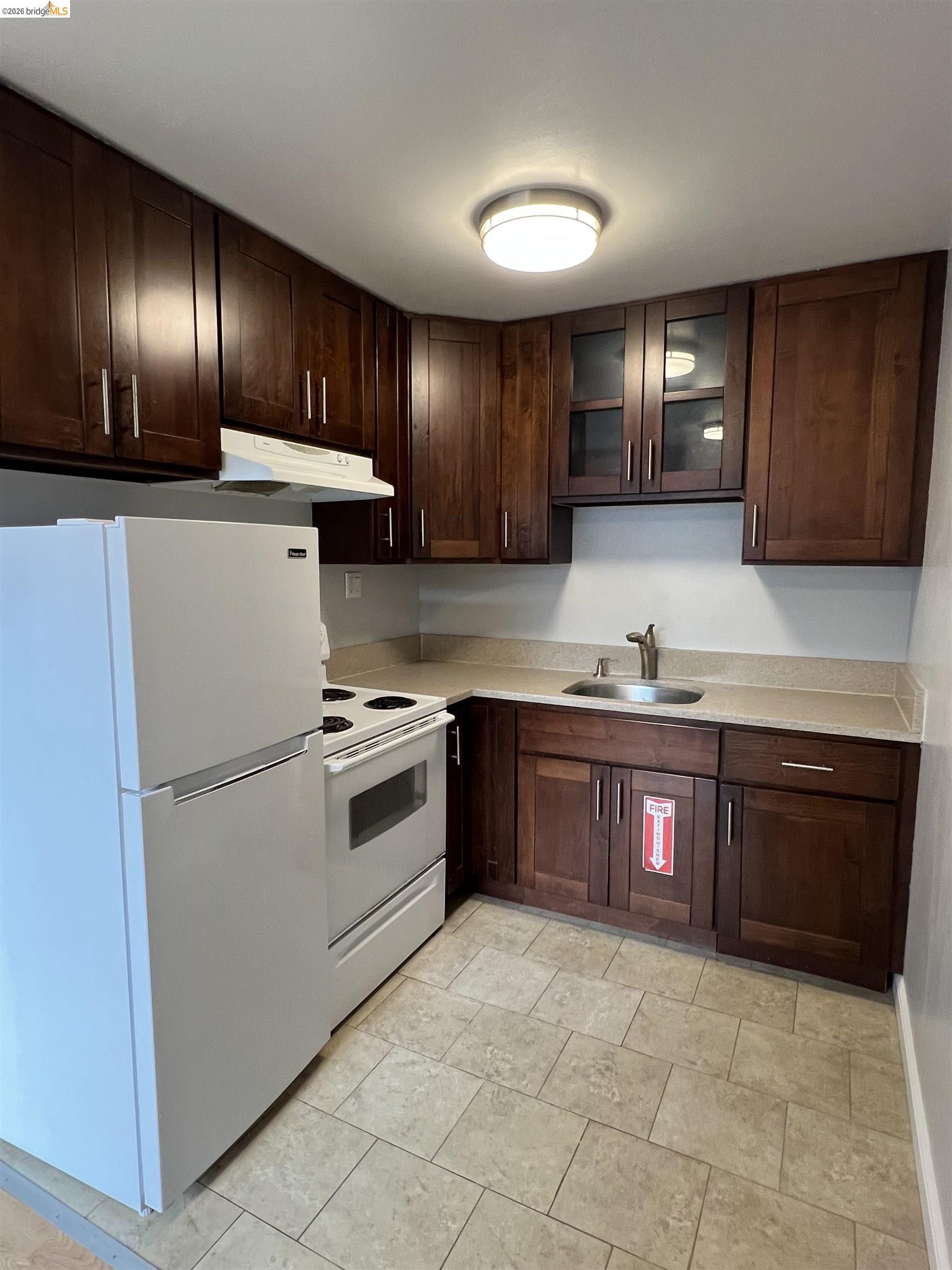 2636 Warring Street, Unit 102 Berkeley, CA 94704 - Photo 3 of 6 a kitchen with granite countertop stainless steel appliances and wooden cabinets