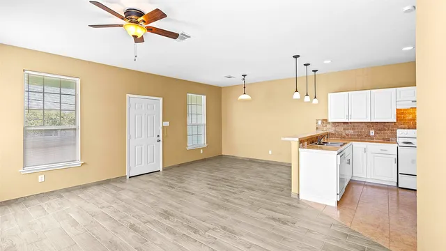 a view of a kitchen with wooden floor and a ceiling fan