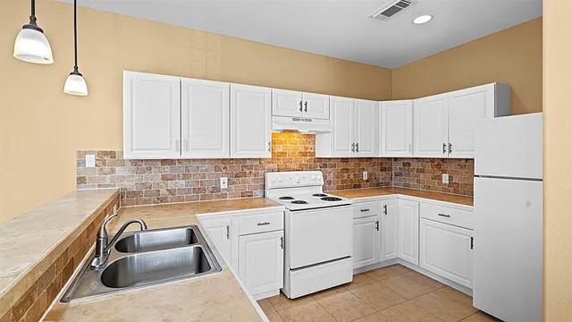 a kitchen with a sink dishwasher and white cabinets with wooden floor