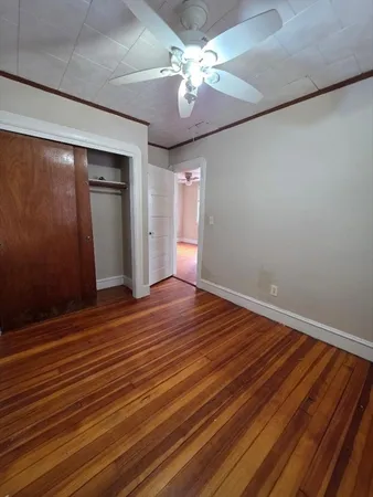 a view of empty room with wooden floor and fan