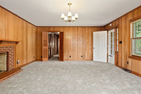 an empty room with chandelier fan and windows