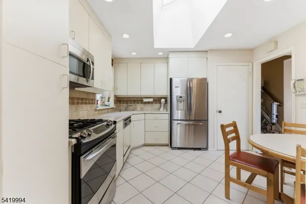 a kitchen with stainless steel appliances a refrigerator stove microwave and white cabinets