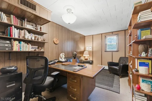a work room with furniture a bookshelf and a window
