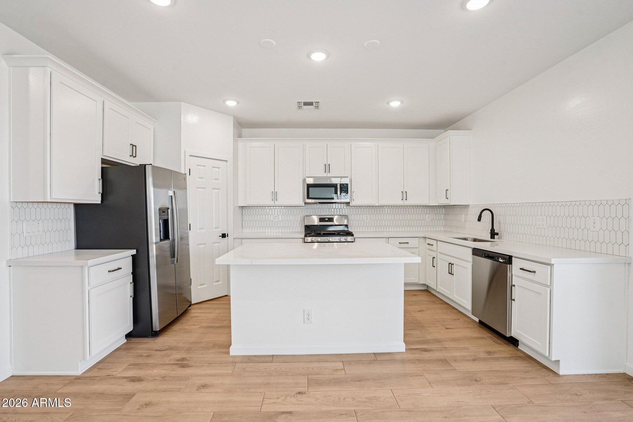 47638 West Moeller Road Maricopa, AZ 85139 - Photo 6 of 56 a kitchen with stainless steel appliances white cabinets a sink a stove a refrigerator and white cabinets