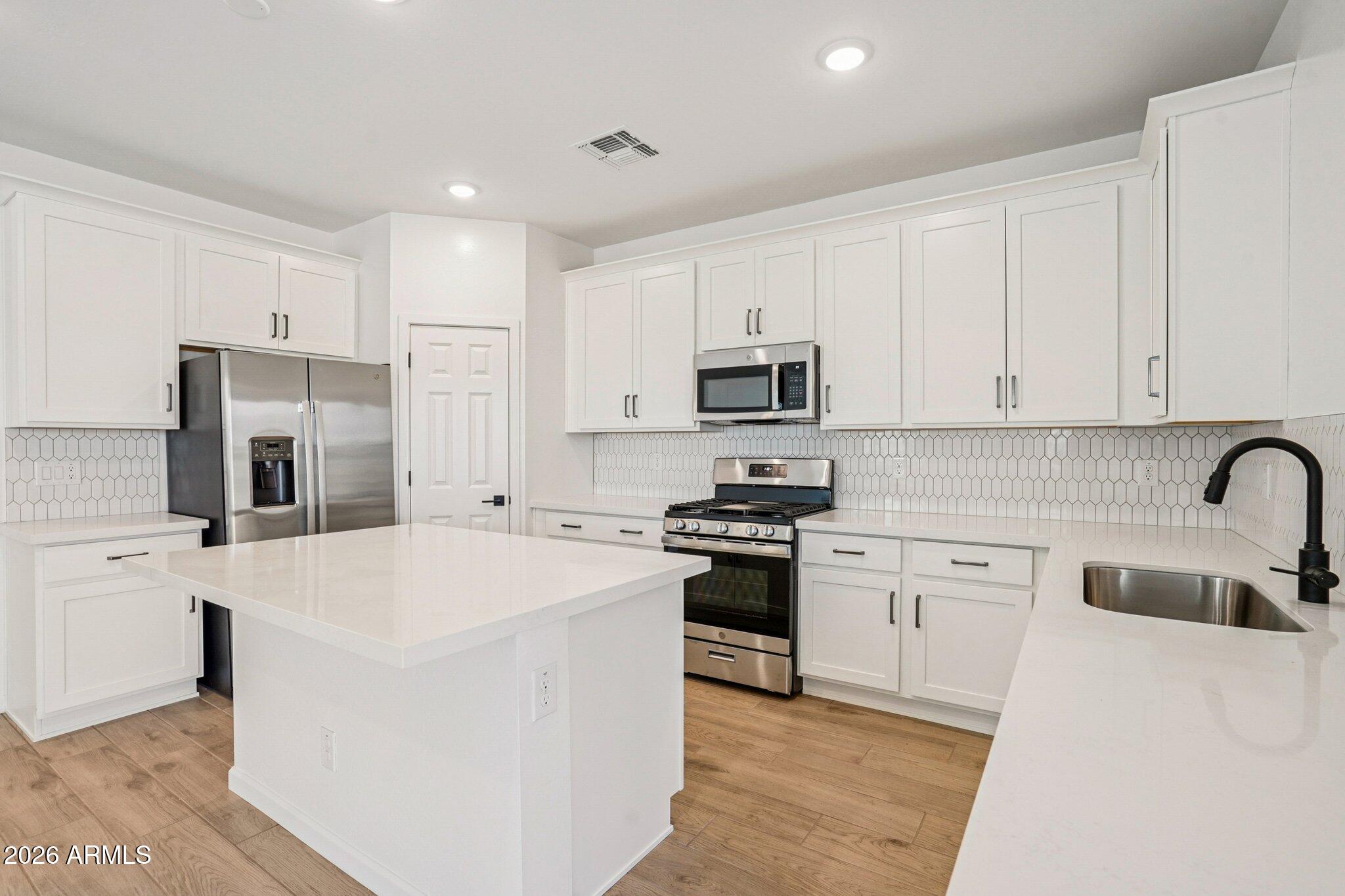 47638 West Moeller Road Maricopa, AZ 85139 - Photo 8 of 56 a kitchen with white cabinets and stainless steel appliances