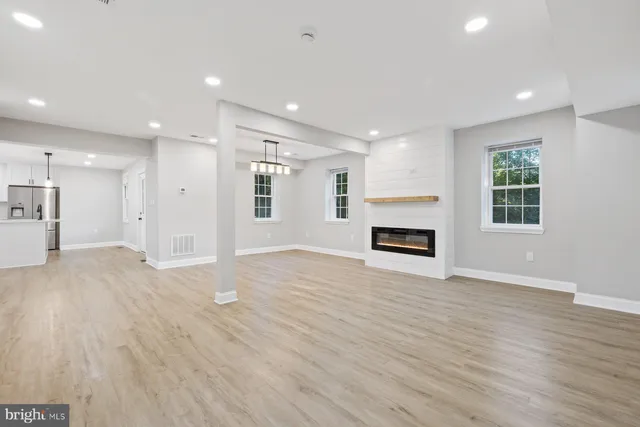 an empty room with wooden floor fireplace and windows
