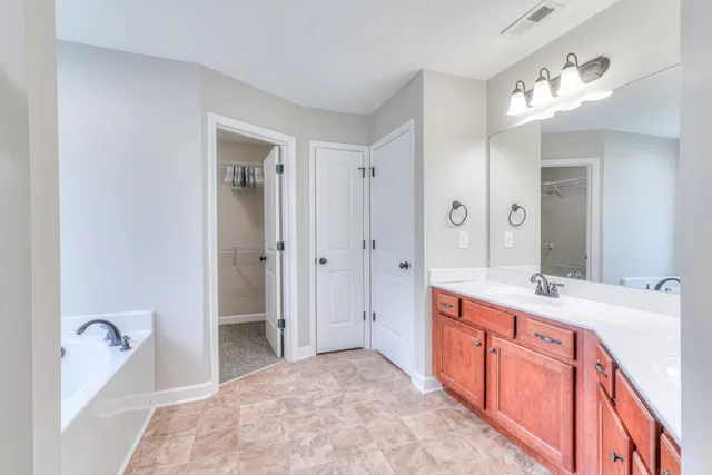 a spacious bathroom with a tub sink and mirror