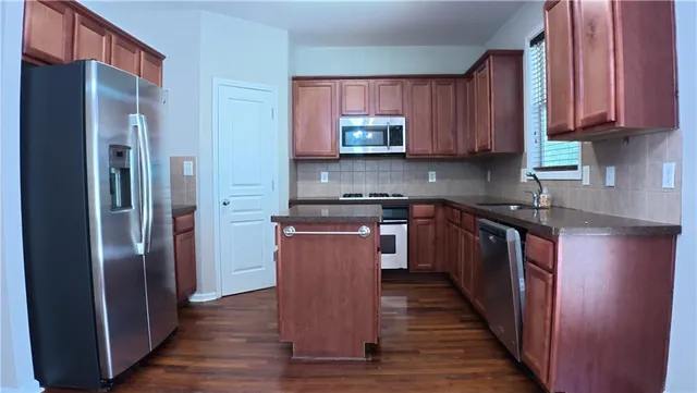 a kitchen with stainless steel appliances granite countertop a refrigerator a sink and wooden cabinets