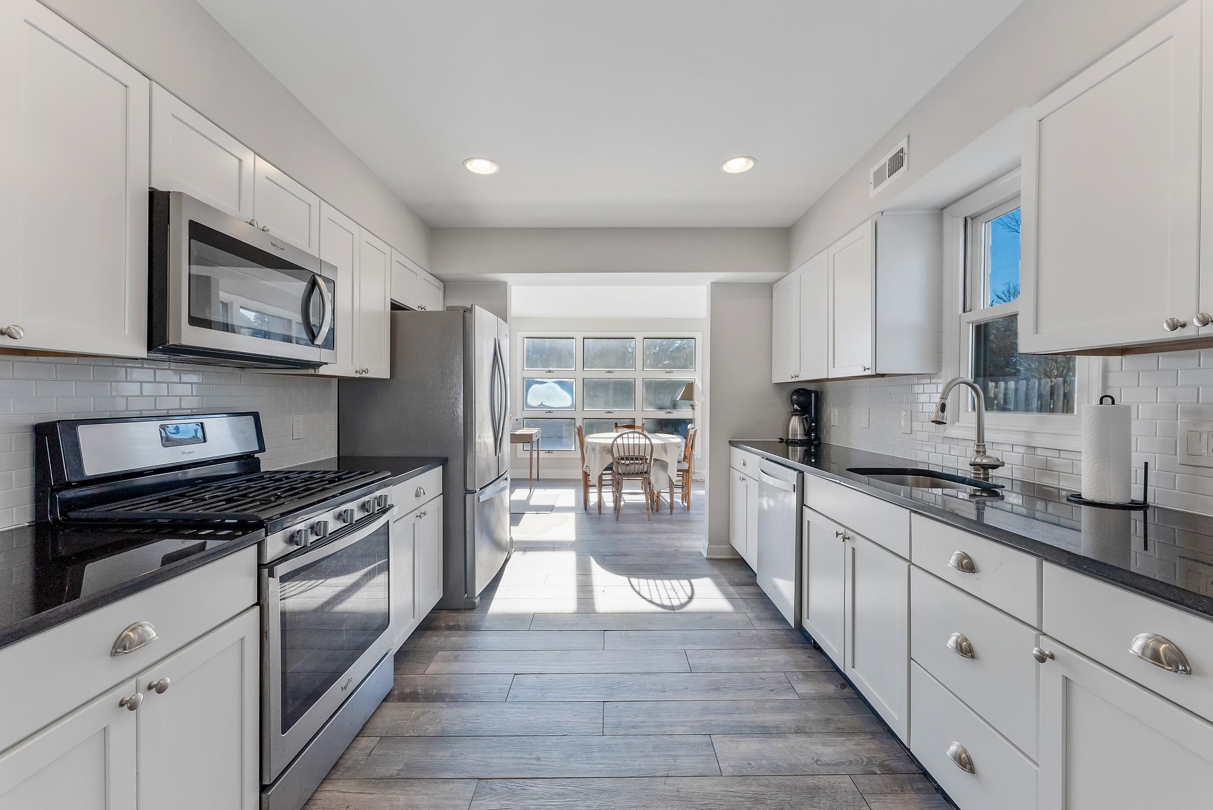 274 52nd Street Avalon, NJ 08202 - Photo 21 of 39 a large kitchen with stainless steel appliances granite countertop a stove top oven a sink dishwasher a dining table and chairs with wooden floor