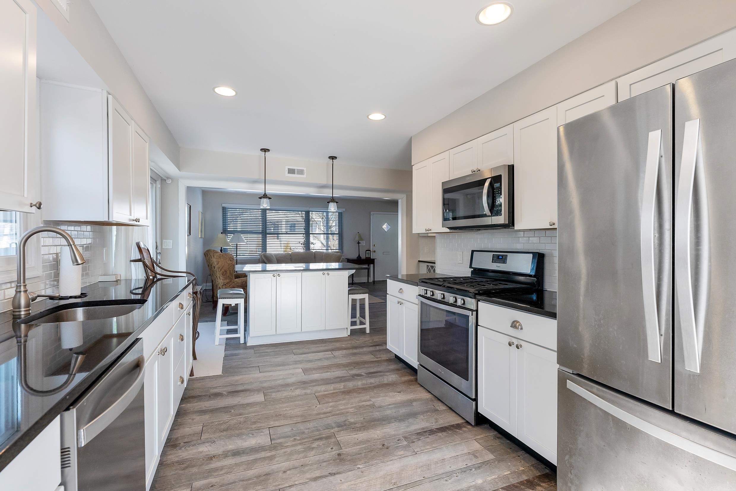 274 52nd Street Avalon, NJ 08202 - Photo 23 of 39 a kitchen with stainless steel appliances a stove top oven a sink a refrigerator white cabinets and wooden floor