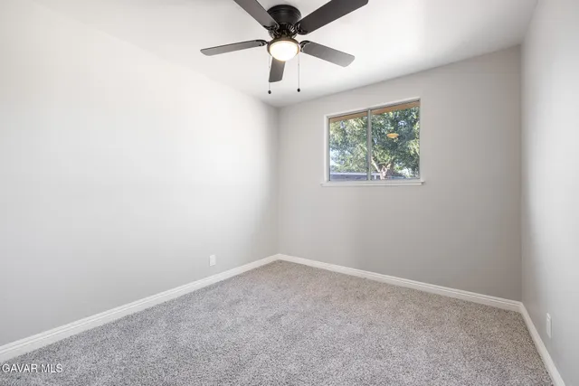 an empty room with a window and a fan