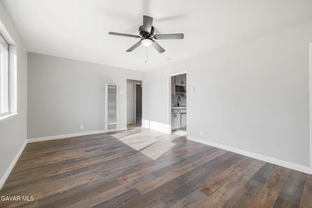 a view of empty room with wooden floor and fan