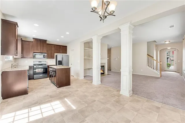 a view of a kitchen with kitchen island stainless steel appliances refrigerator sink and cabinets
