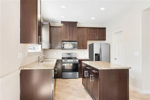 a kitchen with stainless steel appliances granite countertop a refrigerator a stove a sink and a microwave