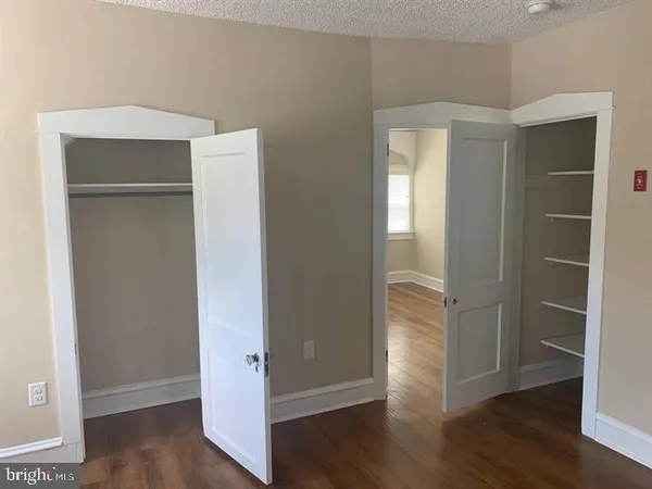 a view of an empty room with wooden floor & closet