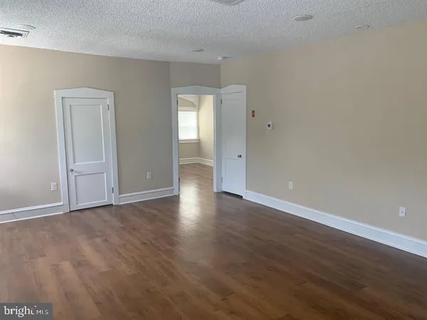 a view of an empty room with wooden floor and closet