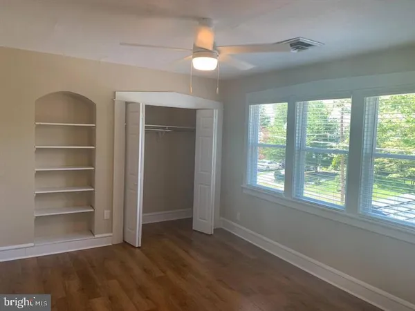 a view of an empty room with a window and wooden floor