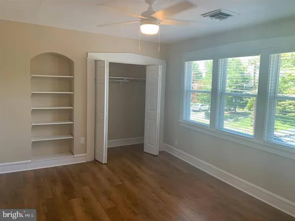 a view of an empty room with a window and wooden floor