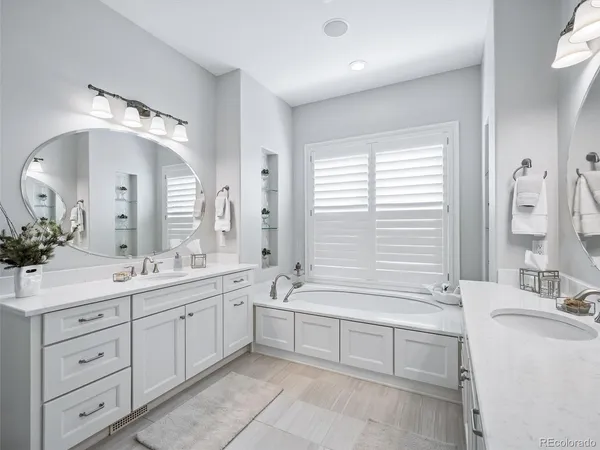 a spacious bathroom with a double vanity sink large mirror and a bathtub