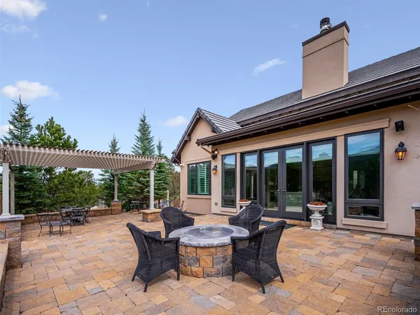 a view of a patio with table and chairs potted plants and floor to ceiling window