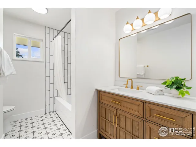 a bathroom with a sink a toilet a mirror a vanity and shower