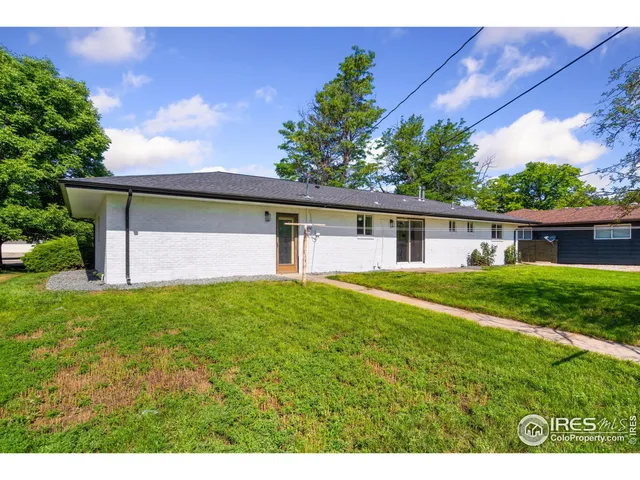 a backyard of a house with plants and large tree