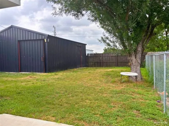 a view of a backyard with a bench and a large tree