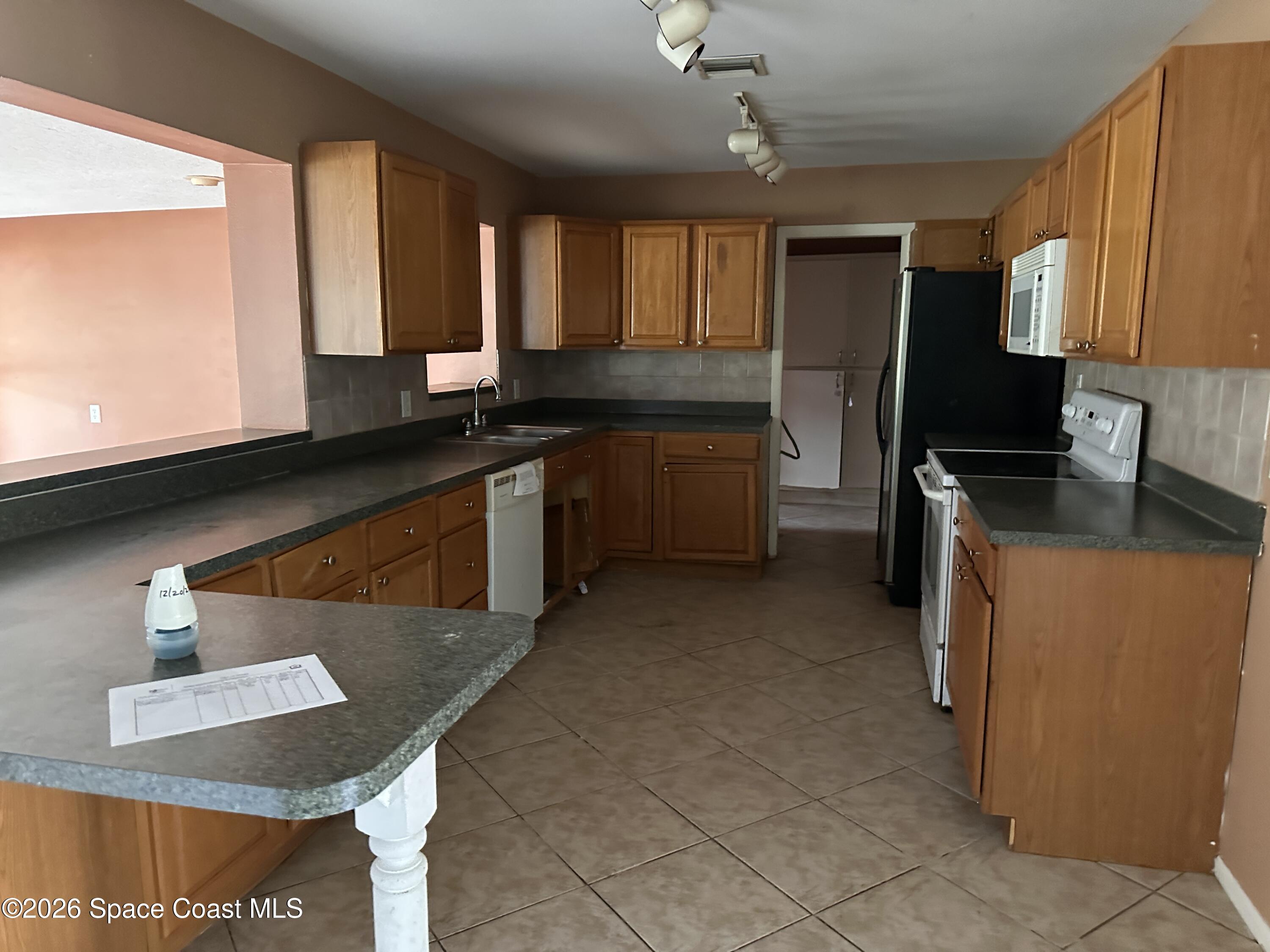 2363 Apache Drive Melbourne, FL 32935 - Photo 11 of 18 a kitchen with stainless steel appliances granite countertop a sink stove and refrigerator