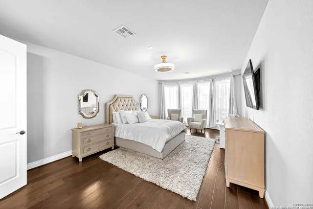 a bedroom with a bed wooden floor and a flat screen tv