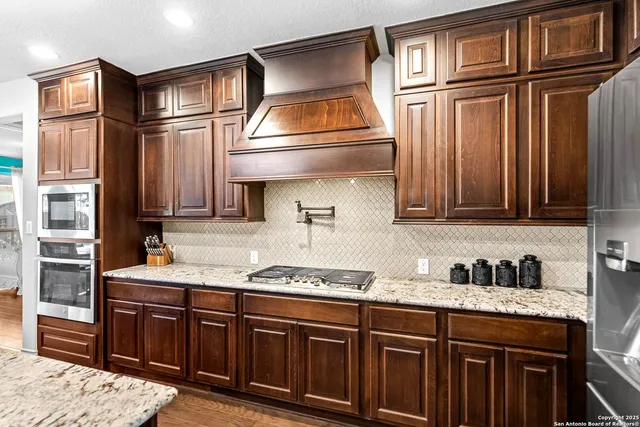 a large kitchen with granite countertop a sink and a stove top oven with wooden floor