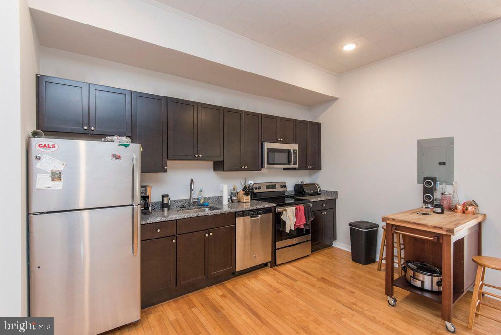 237 Bridge Street, Unit 401 Phoenixville, PA 19460 - Photo 2 of 8 a kitchen with stainless steel appliances granite countertop a refrigerator stove a sink dishwasher and a refrigerator with wooden floor