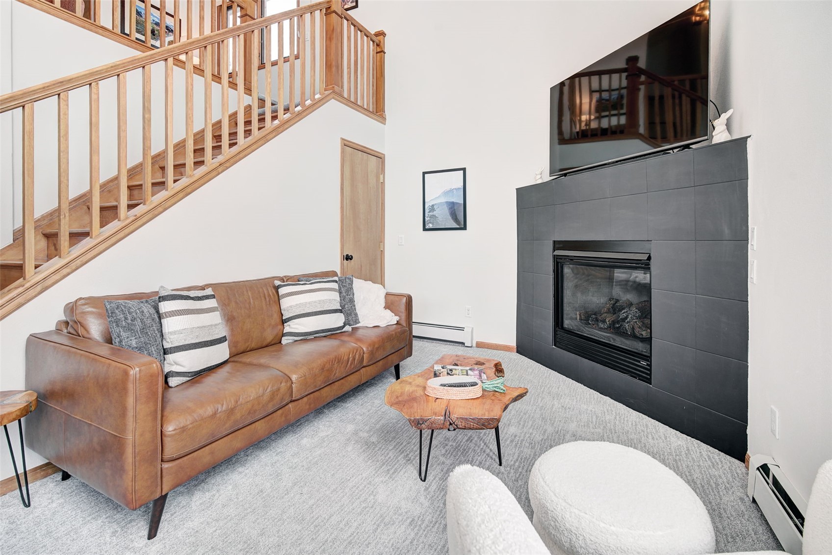 3710 Ryan Gulch Road, Unit 378 Silverthorne, CO 80498 - Photo 5 of 31 Living area with a high ceiling, a tiled fireplace, a baseboard radiator, and carpet