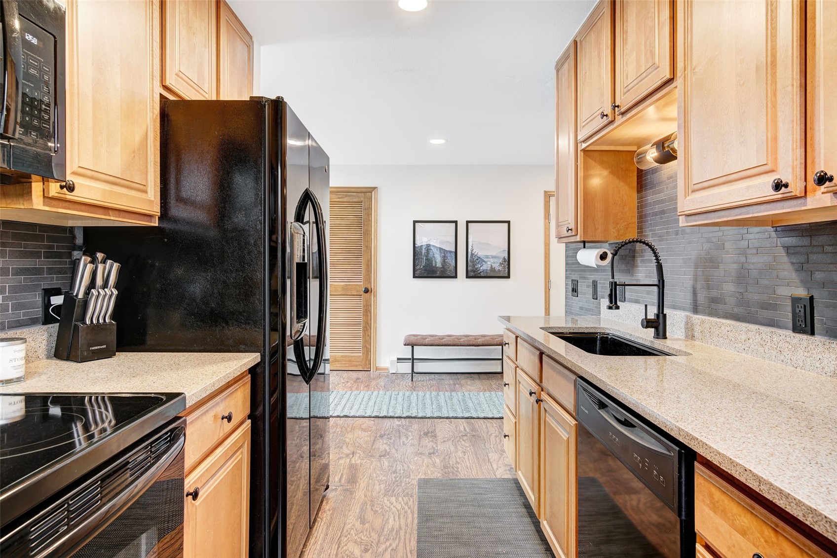 3710 Ryan Gulch Road, Unit 378 Silverthorne, CO 80498 - Photo 9 of 31 Kitchen with decorative backsplash, light stone countertops, black appliances, light wood finish cabinets, and recessed lighting