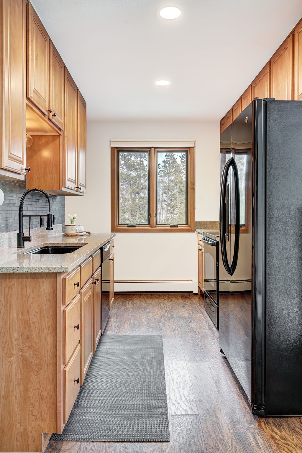 3710 Ryan Gulch Road, Unit 378 Silverthorne, CO 80498 - Photo 10 of 31 Kitchen with light stone countertops, black appliances, recessed lighting, light wood-style flooring, and baseboard heating