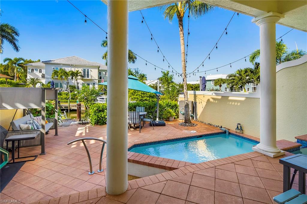1160 Clam Court, Unit 3 Naples, FL 34102 - Photo 38 of 50 a view of a patio with dining table and chairs under an umbrella