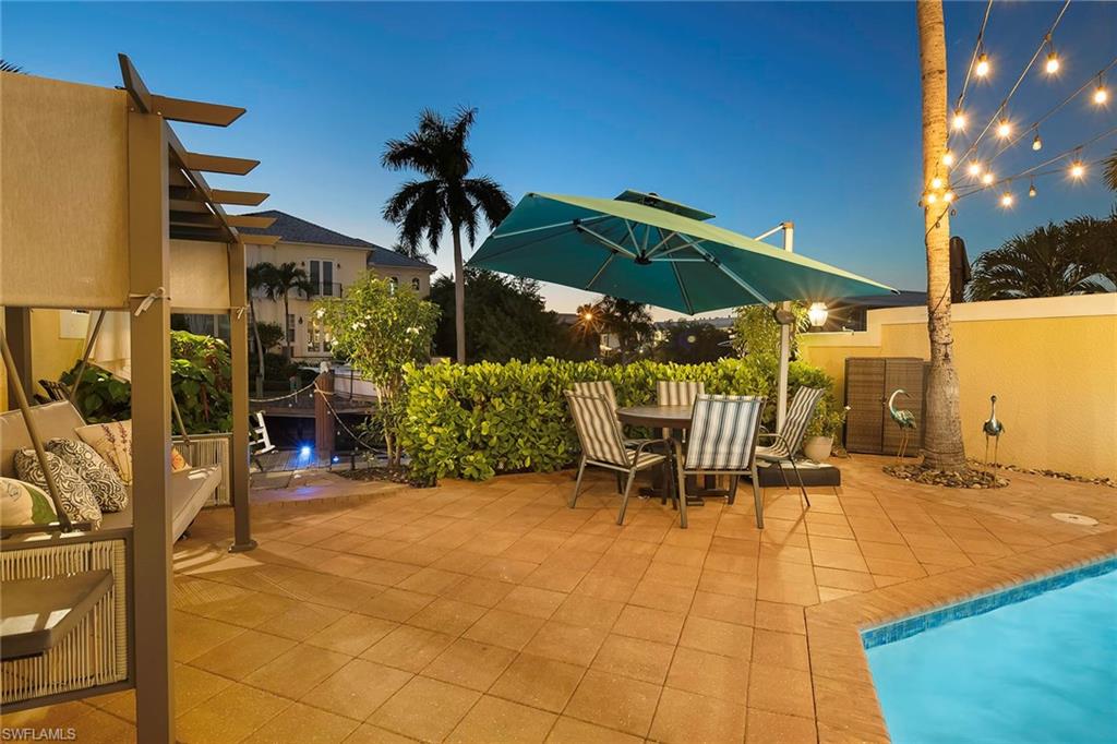 1160 Clam Court, Unit 3 Naples, FL 34102 - Photo 48 of 50 a view of a patio with table and chairs under an umbrella