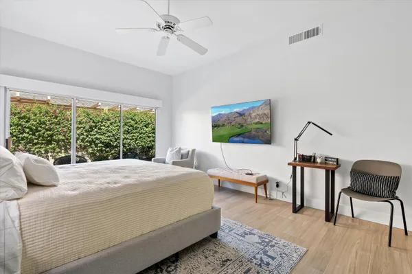 a bedroom with a bed wooden floor and a large window