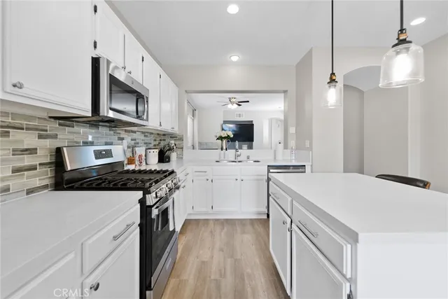 a kitchen with stainless steel appliances a stove a sink a microwave a refrigerator a stove and white cabinets