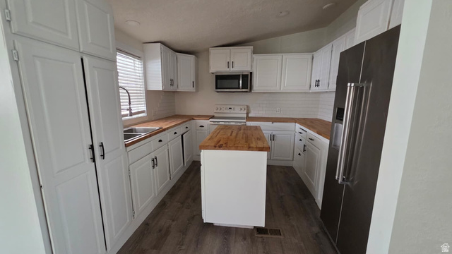 1450 North Dixie Downs Road, Unit 51 St. George, UT 84770 - Photo 4 of 25 Kitchen featuring white cabinetry, wood-finish countertops, stainless steel appliances, a center island, and wood-finish flooring