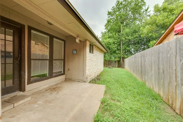 a view of backyard with large trees and wooden fence