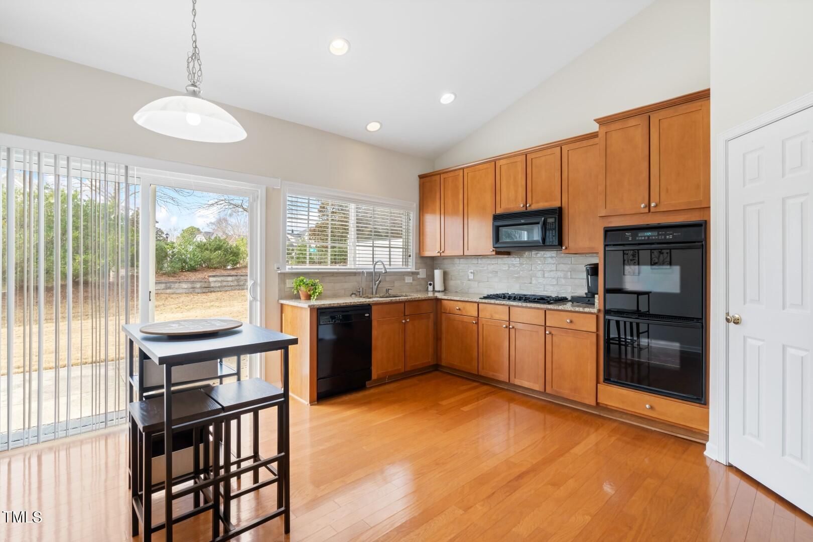 12219 Fox Valley Street Raleigh, NC 27614 - Photo 12 of 36 a kitchen with stainless steel appliances granite countertop a stove top oven a sink dishwasher a dining table and chairs with wooden floor