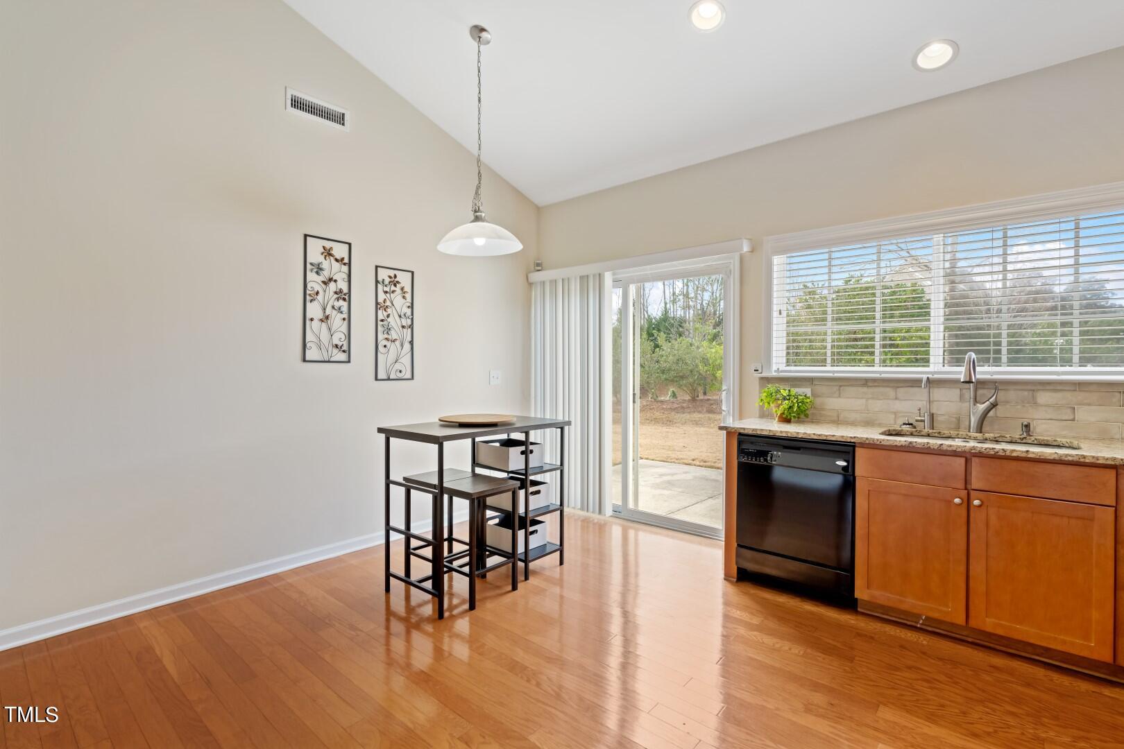 12219 Fox Valley Street Raleigh, NC 27614 - Photo 13 of 36 a open kitchen with granite countertop a stove a sink a dining table and chairs with wooden floor