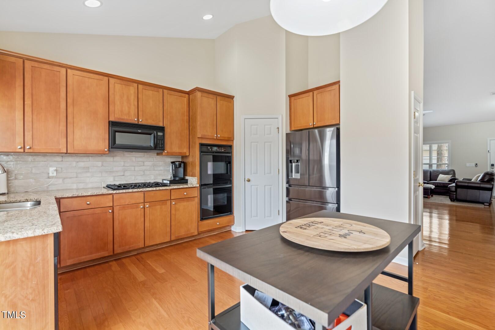 12219 Fox Valley Street Raleigh, NC 27614 - Photo 14 of 36 a kitchen with stainless steel appliances granite countertop a stove top oven a sink a dining table and chairs with wooden floor