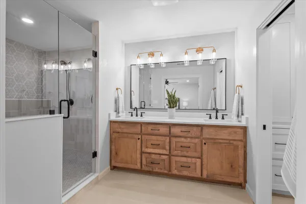 a spacious bathroom with a double vanity sink a large mirror and shower