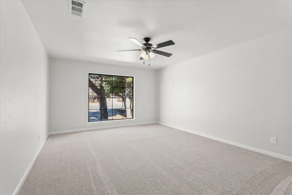 an empty room with windows and ceiling fan view
