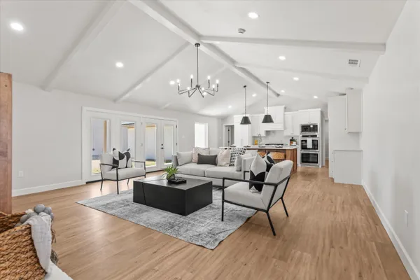a living room with furniture kitchen view and a chandelier