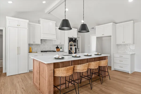 a kitchen with stainless steel appliances granite countertop a sink a stove a refrigerator and island with wooden floor